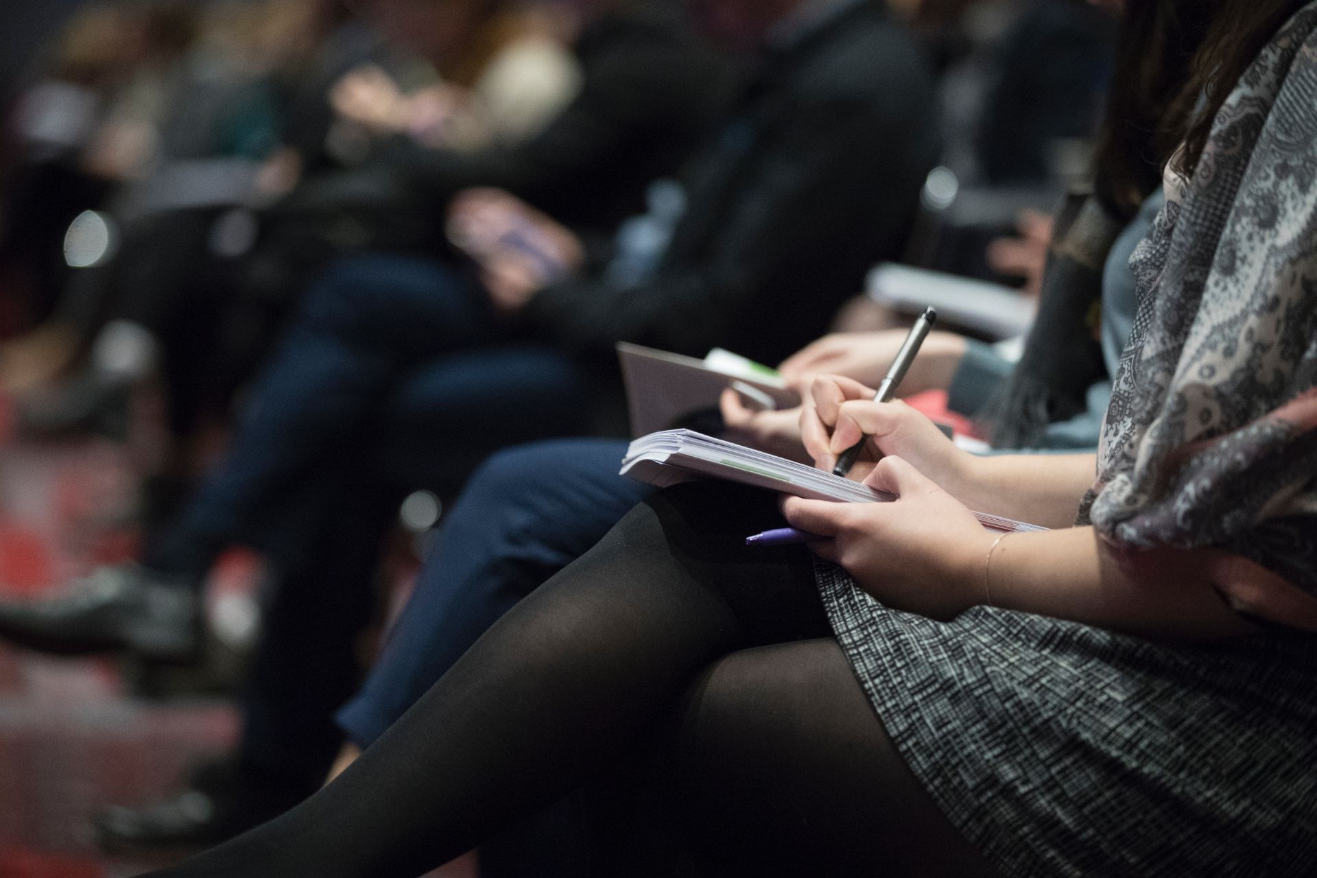 photo of line of people sitting and writing in notebooks