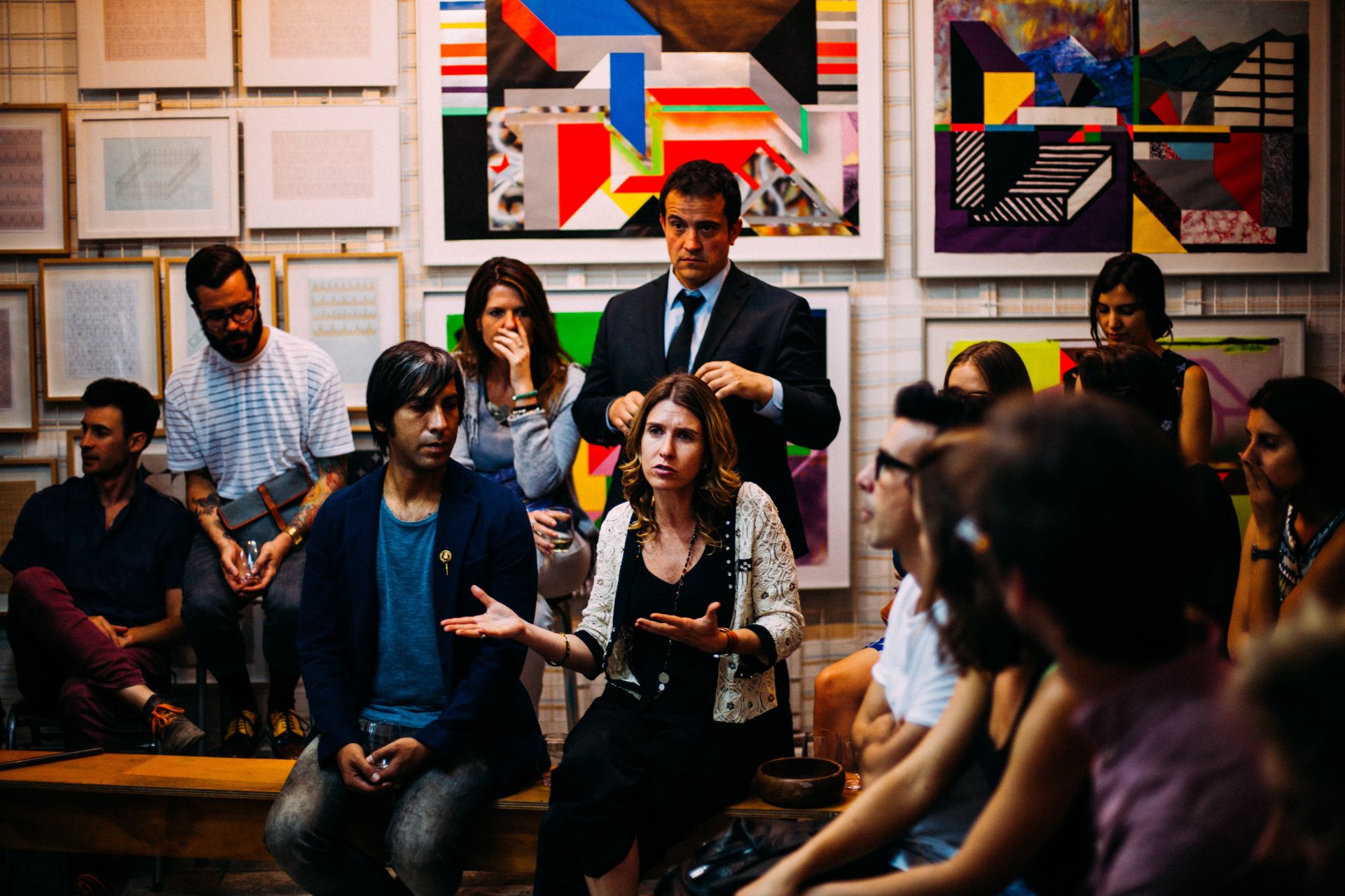 photo of group of people sitting on benches in front of artwork