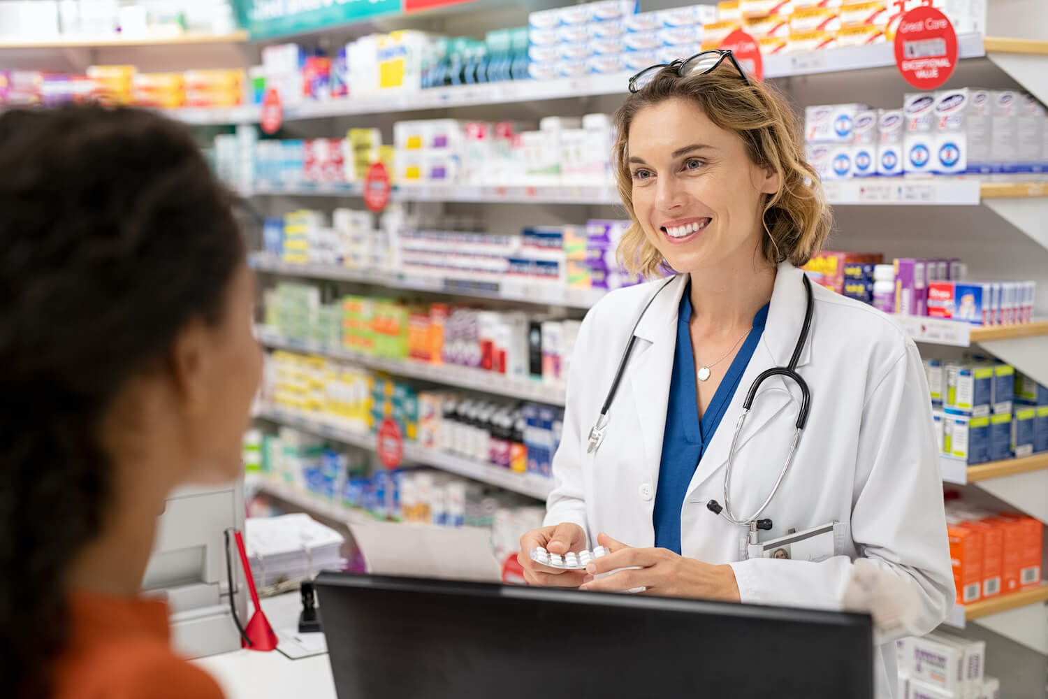 pharmacist smiling behind counter at female patient